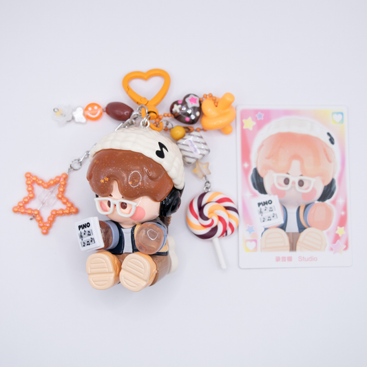 Orange heart keychain with Pino Jelly SStudio figure from Pop Mart's Star Project Series with matching charms including lollipop, star, notes, heart) next to its card