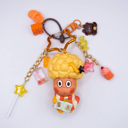 Star keychain with Twinkle Twinkle HAIRCUT figure from the Be A Little Star Series with matching orange-tones charms including star lollipop, muffin, stars, candy, lego piece, croc.