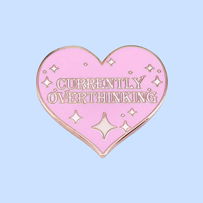 Pink heart-shaped pin with 'Currently Overthinking' text on a light blue background
