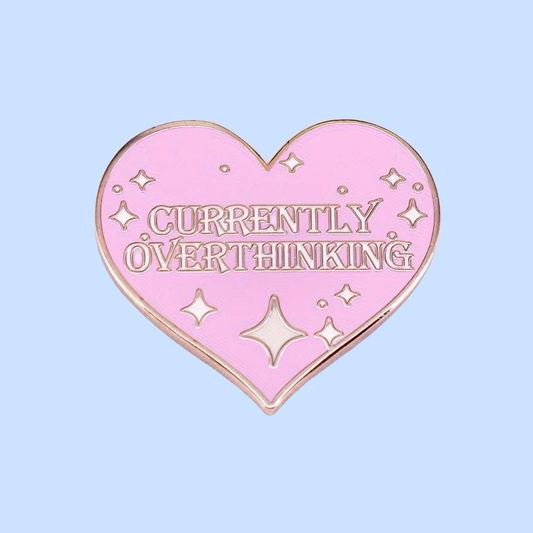 Pink heart-shaped pin with 'Currently Overthinking' text on a light blue background