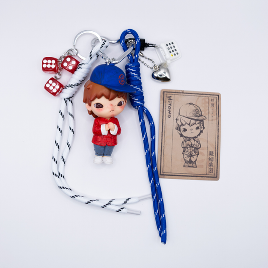 Silver heart keychain with Hirono Silk Royale figure from POP MART's Clot series and matching charms including blue lanyard, black and white lanyard, silver heart, white rotary phone, three red dice next to its card.