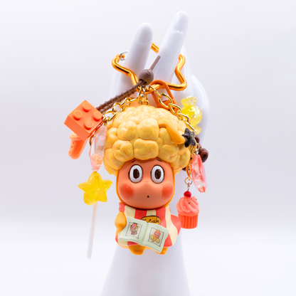 Star keychain with Twinkle Twinkle HAIRCUT figure from the Be A Little Star Series with matching orange-tones charms including star lollipop, muffin, stars, candy, lego piece, croc.