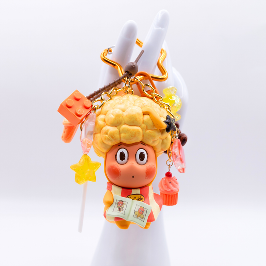 Star keychain with Twinkle Twinkle HAIRCUT figure from the Be A Little Star Series with matching orange-tones charms including star lollipop, muffin, stars, candy, lego piece, croc.