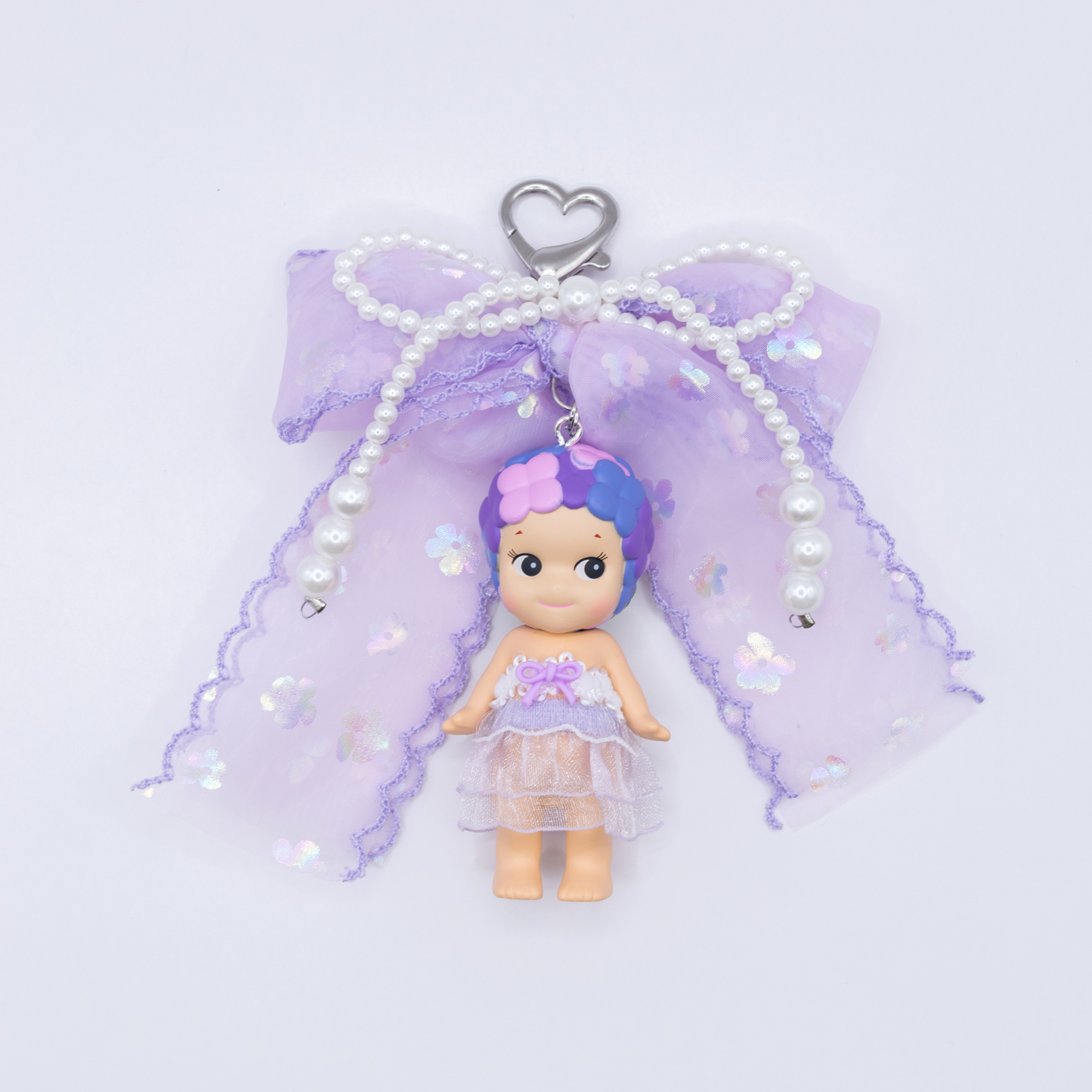 Silver heart keychain featuring Sonny Angel HYDRANGEA figure from the Flower series with a purple sequined bow and faux pearls on a white background