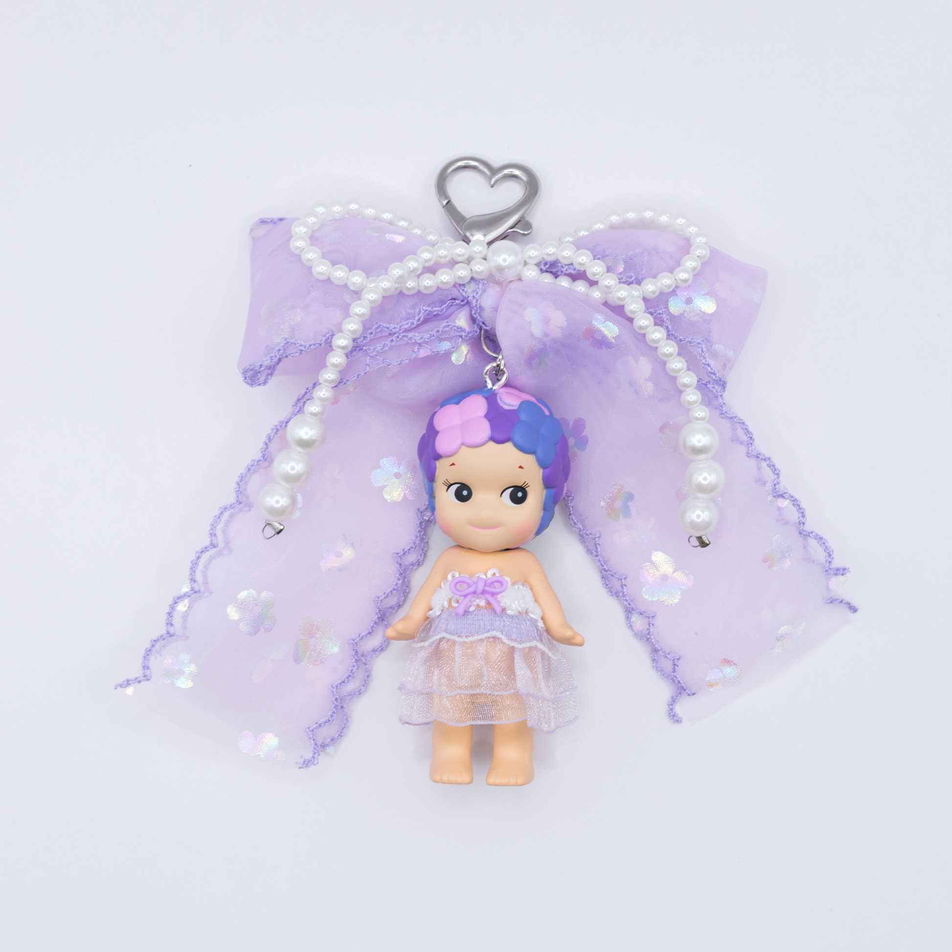 Silver heart keychain featuring Sonny Angel HYDRANGEA figure from the Flower series with a purple sequined bow and faux pearls on a white background