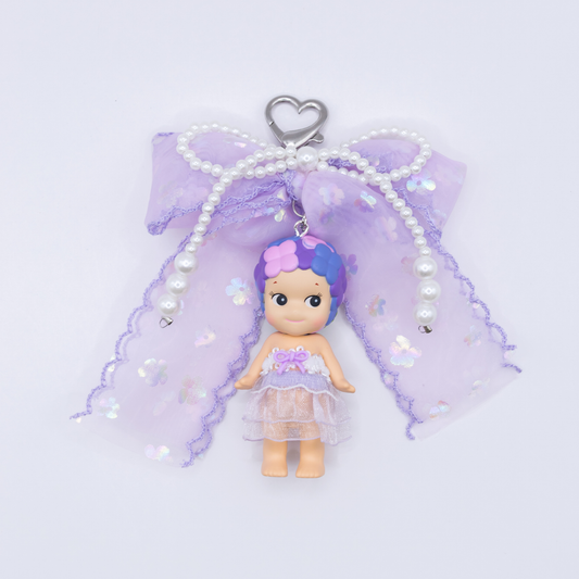 Silver heart keychain featuring Sonny Angel HYDRANGEA figure from the Flower series with a purple sequined bow and faux pearls on a white background