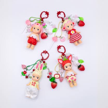 Four Sonny Angel keychains with figures from the Strawberry Love series on a red strawberry clasps with matching beads
