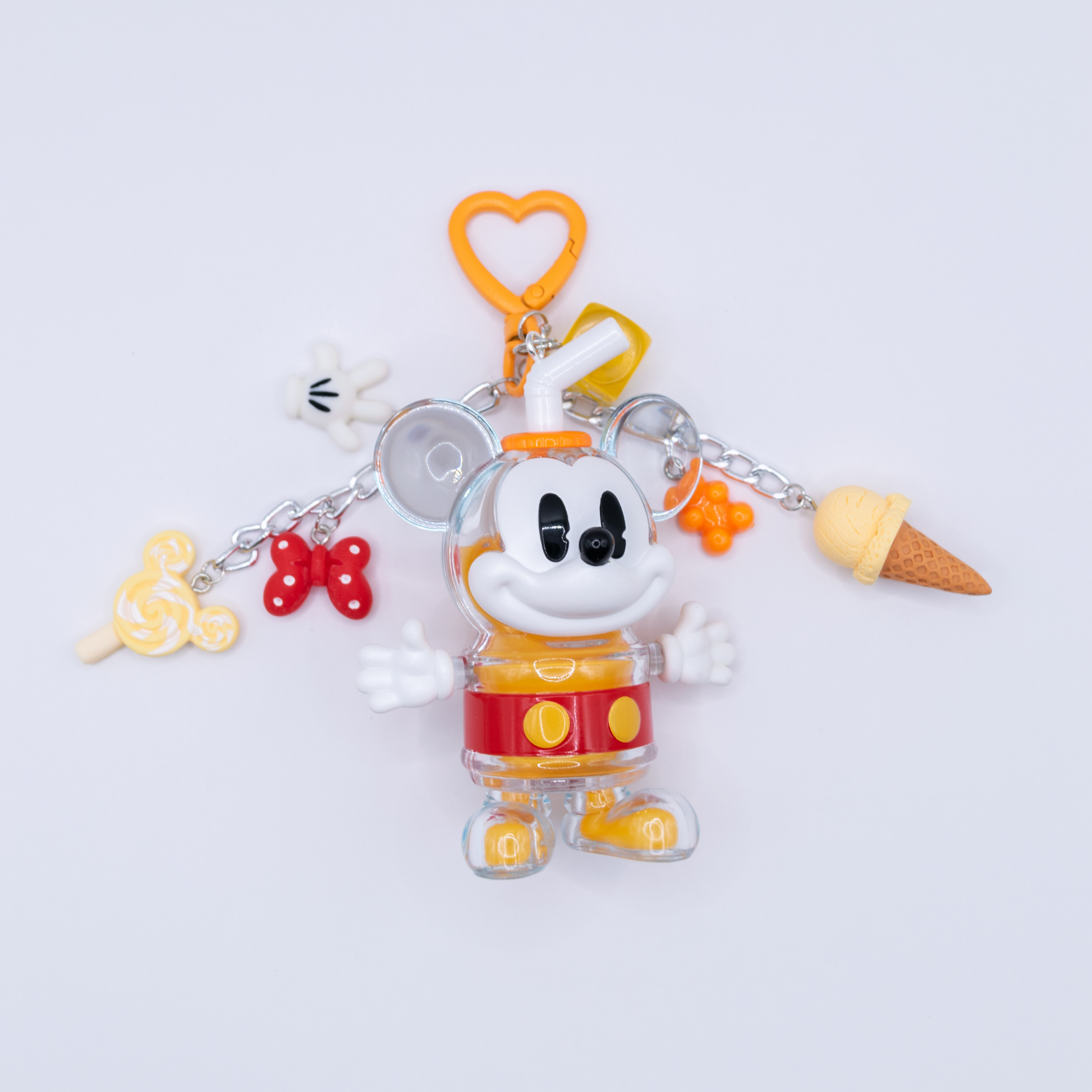 A Mickey Mouse-themed acrylic charm keychain featuring a clear Mickey figure in a yellow and red outfit, surrounded by small dangling charms including a lollipop, bow tie, ice cream cone, and heart-shaped clip, photographed on a clean white background.
