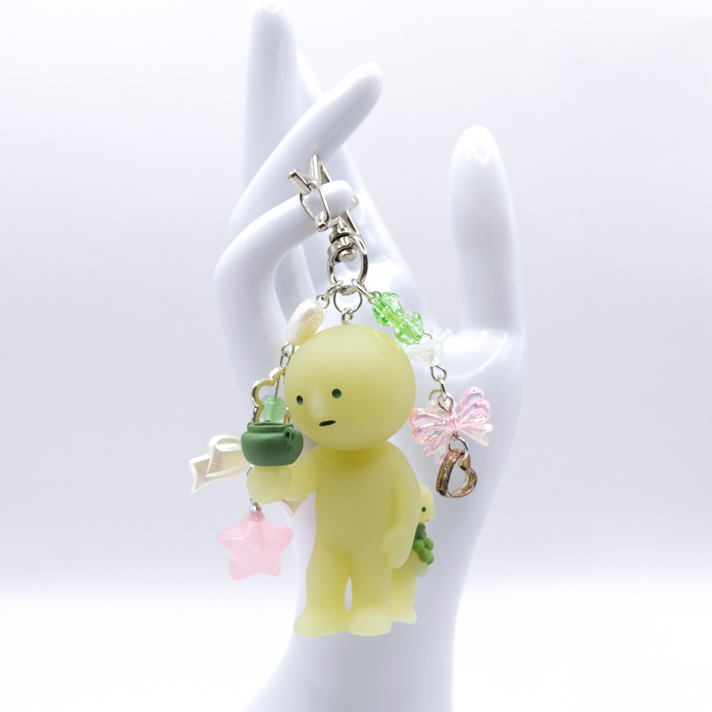Keychain with Smiski Bacchus figure from the Museum series with star clasp and matching charms on a white hand stand