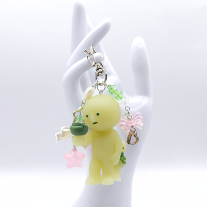 Keychain with Smiski Bacchus figure from the Museum series with star clasp and matching charms on a white hand stand