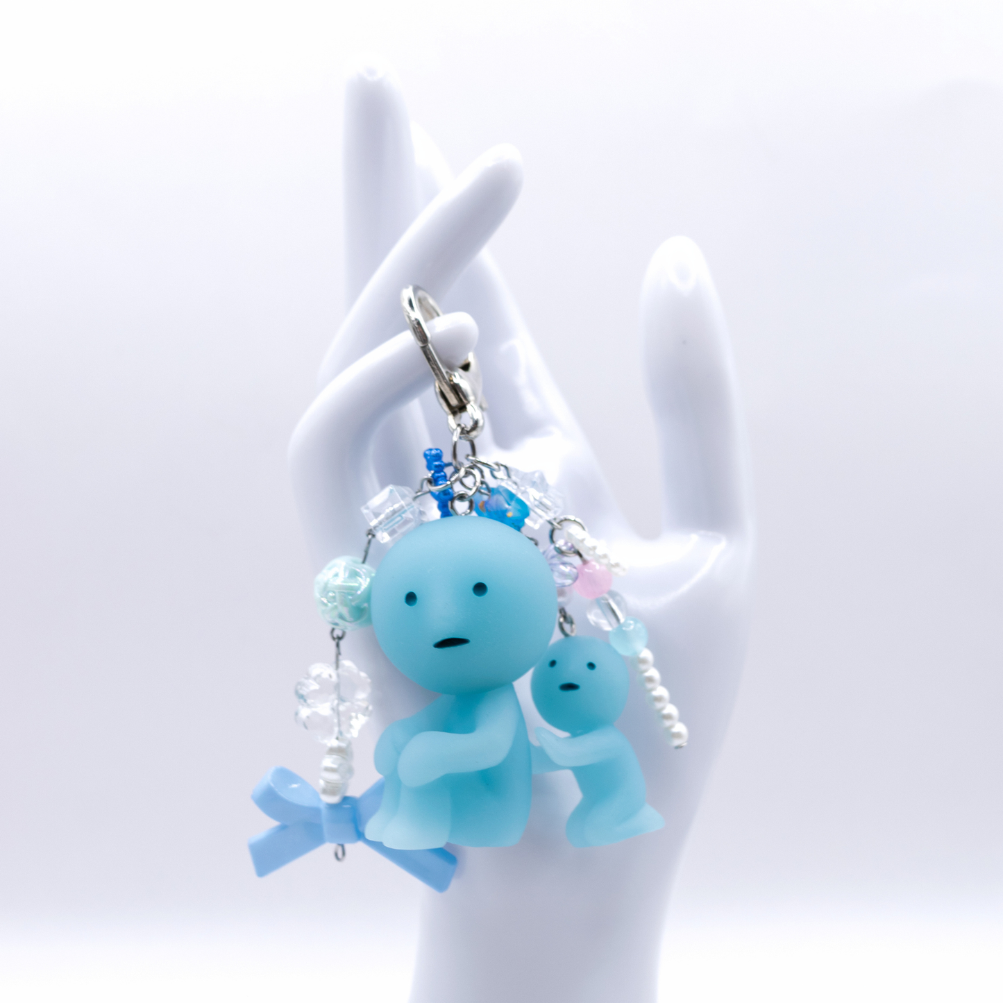 Keychain with Smiski Scrubbing figure from the bath series with heart clasp and matching charms on a white hand display