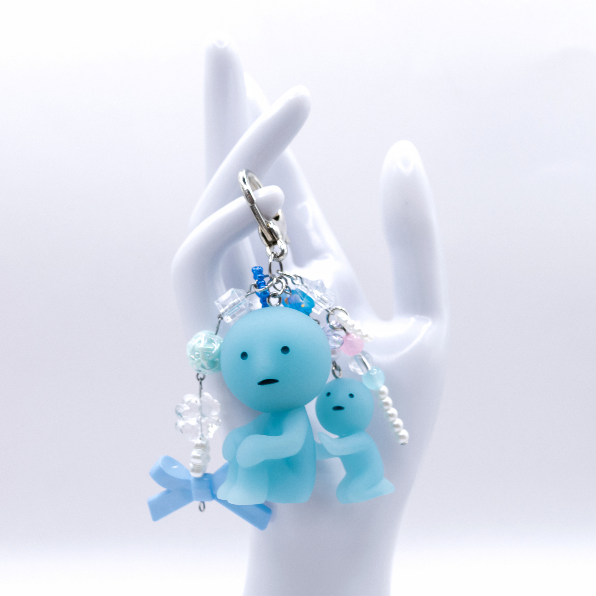 Keychain with Smiski Scrubbing figure from the bath series with heart clasp and matching charms on a white hand display