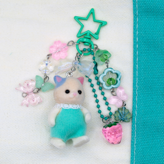 Sylvanian family CAT with mint color overalls and matching flower, butterfly, and strawberry acrylic charms in mint, pink and clear color