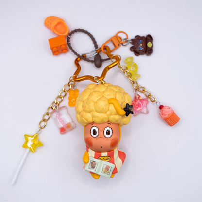 Star keychain with Twinkle Twinkle HAIRCUT figure from the Be A Little Star Series with matching orange-tones charms including star lollipop, muffin, stars, candy, lego piece, croc.