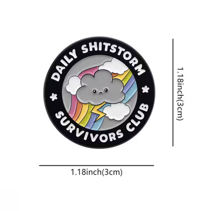 Button badge with cloud and rainbow design and text 'Daily Shitstorm Survivors Club' on a white background.
