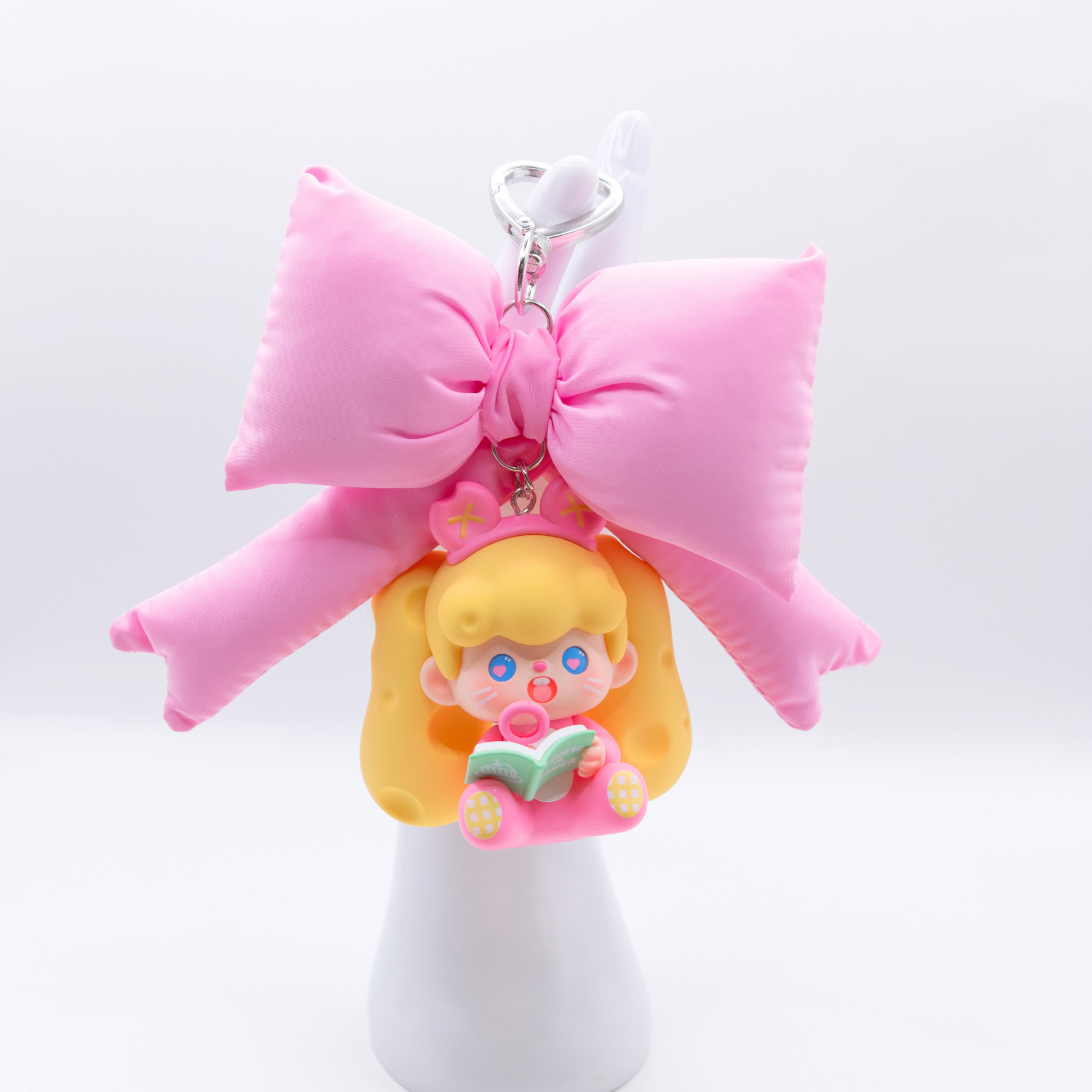 Heart keychain featuring Supertutu figure from Pop Mart's HAPPY-ING! Series and a pink bow on a white hand stand