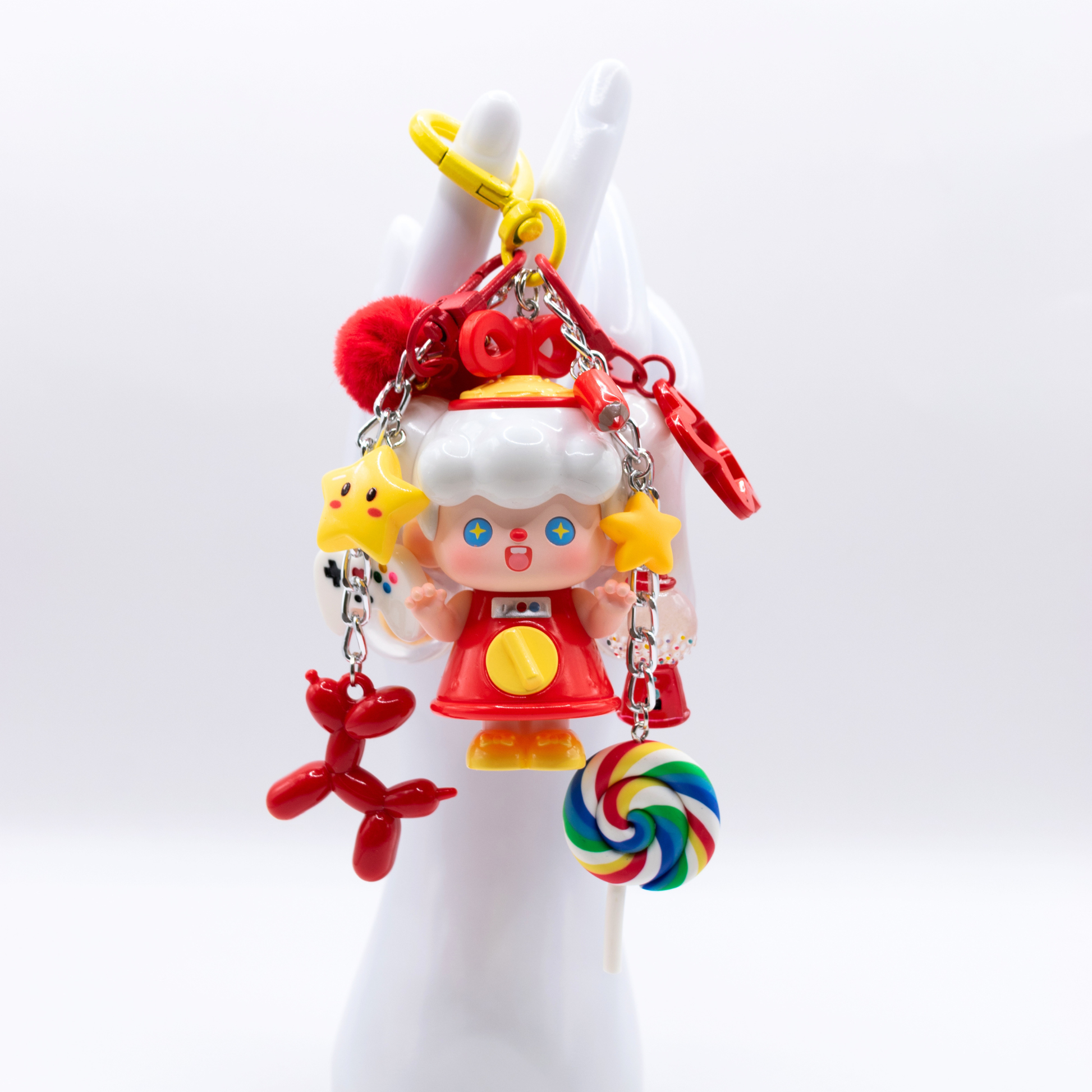 Heart keychain featuring Supertutu GAME START figure from Pop Mart's HAPPY-ING! Series and matching colorful charms on white hand stand
