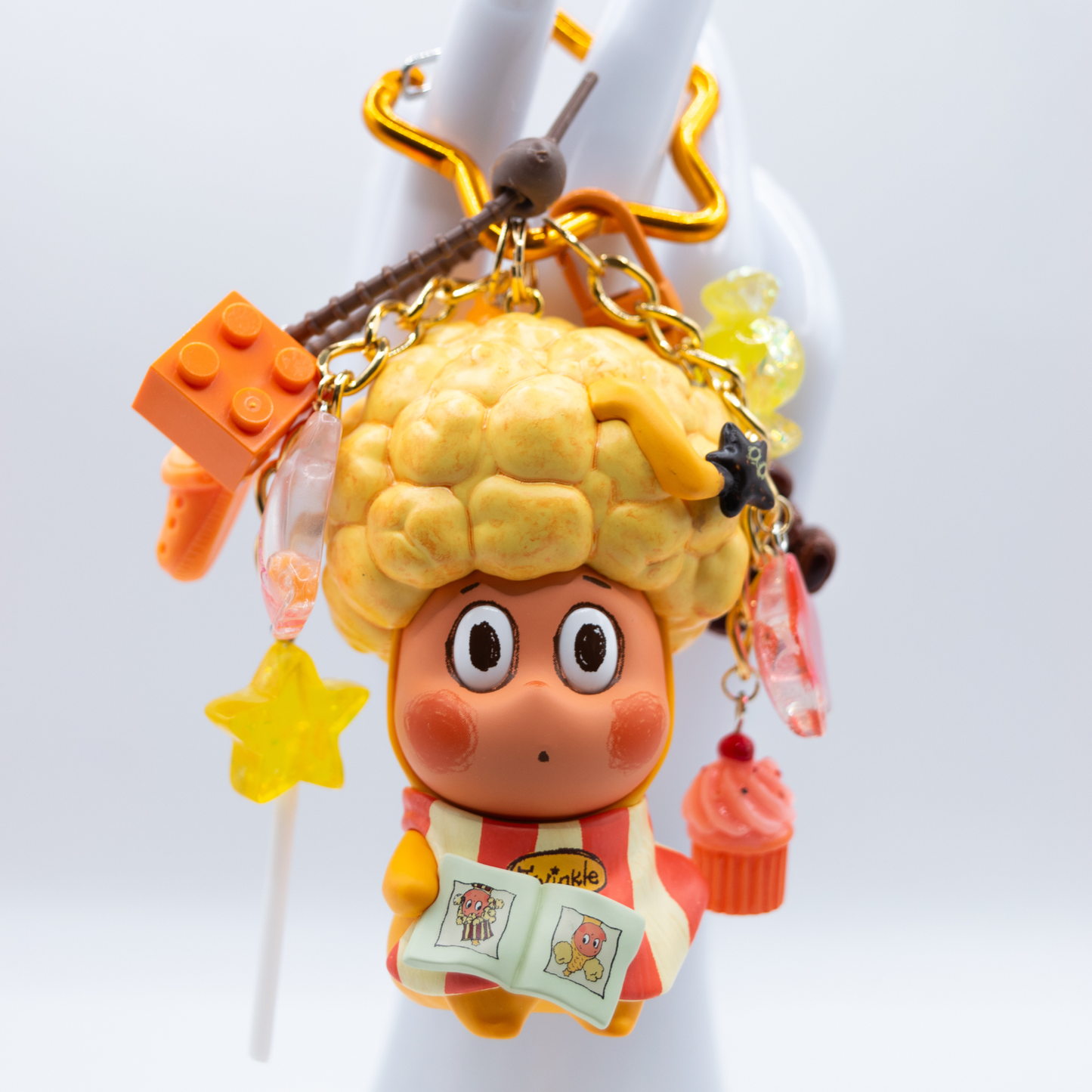 Star keychain with Twinkle Twinkle HAIRCUT figure from the Be A Little Star Series with matching orange-tones charms including star lollipop, muffin, stars, candy, lego piece, croc.