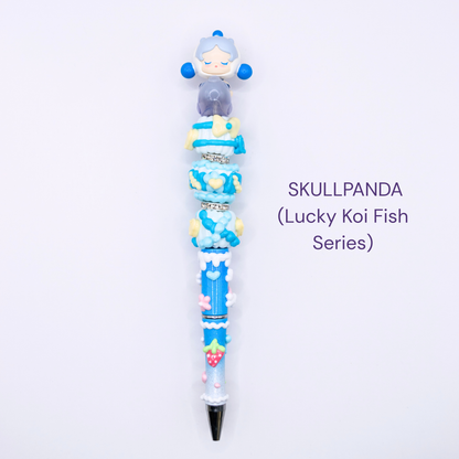 Colorful beaded pen with cartoon character design on a white background, labeled 'SKULLPANDA Lucky Koi Fish Series'.